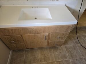 A newly installed bathroom vanity with a white sink and light wood cabinets by Just-In-Time Handyman Services in Honolulu, HI.