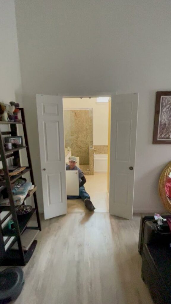 A worker installing a bathroom vanity during a renovation project by Brewer Builds in Fort Worth, TX.