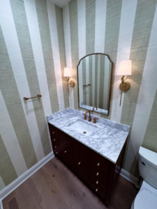 A modern bathroom vanity with a marble top, sink, mirror, and wall sconces installed by Shipe Builders in Salisbury, MD.