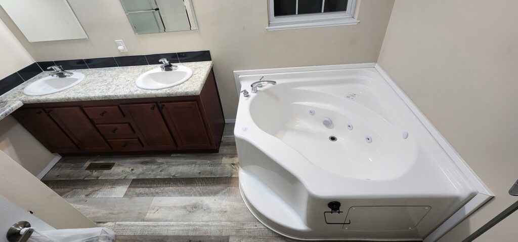 Newly installed bathroom vanity with double sinks and a corner jetted tub by SAM'S Handywork LLC in Independence, IA.