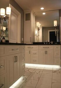 A modern bathroom vanity with under-cabinet lighting and marble flooring by J Brothers Design- Build- Remodel, Inc. in Corcoran, MN