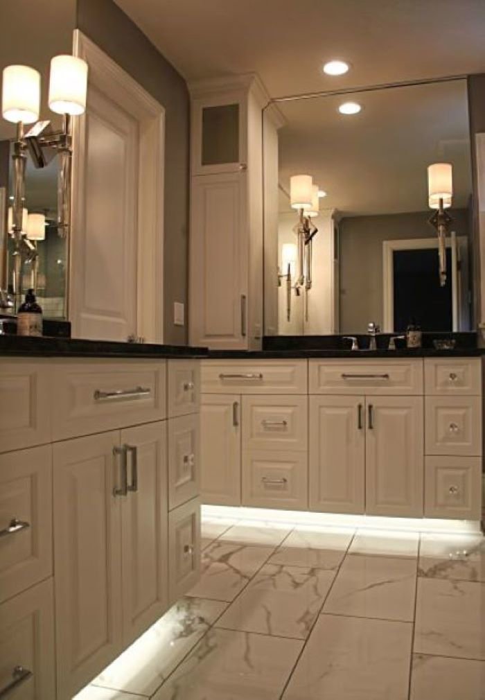 A modern bathroom vanity with under-cabinet lighting and marble flooring by J Brothers Design- Build- Remodel, Inc. in Corcoran, MN