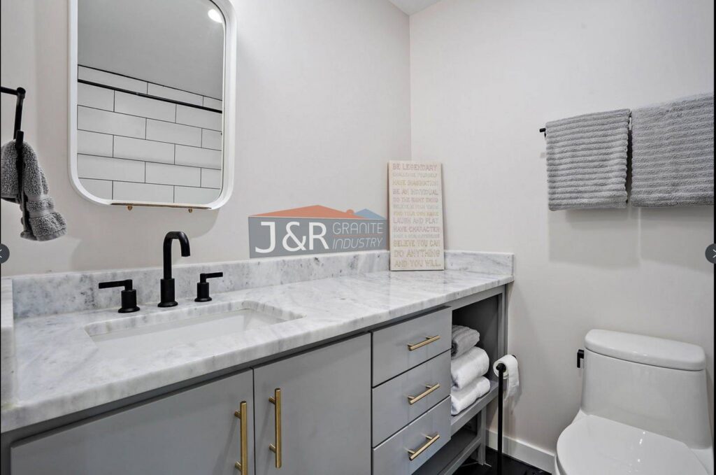 Bathroom vanity with a white marble countertop and modern black fixtures installed by J and R Granite Industry in Columbus, OH.