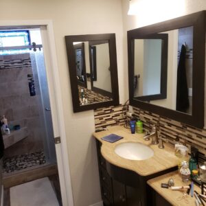 A renovated bathroom vanity area with new mirrors, tile backsplash, and faucet installed by McCarran Handyman Services in Boulder City, NV.
