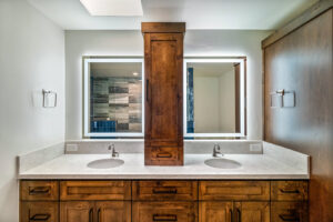 A custom bathroom vanity with double sinks, wooden cabinets, and modern backlit mirrors installed by Ignite Construction in Tempe, AZ.