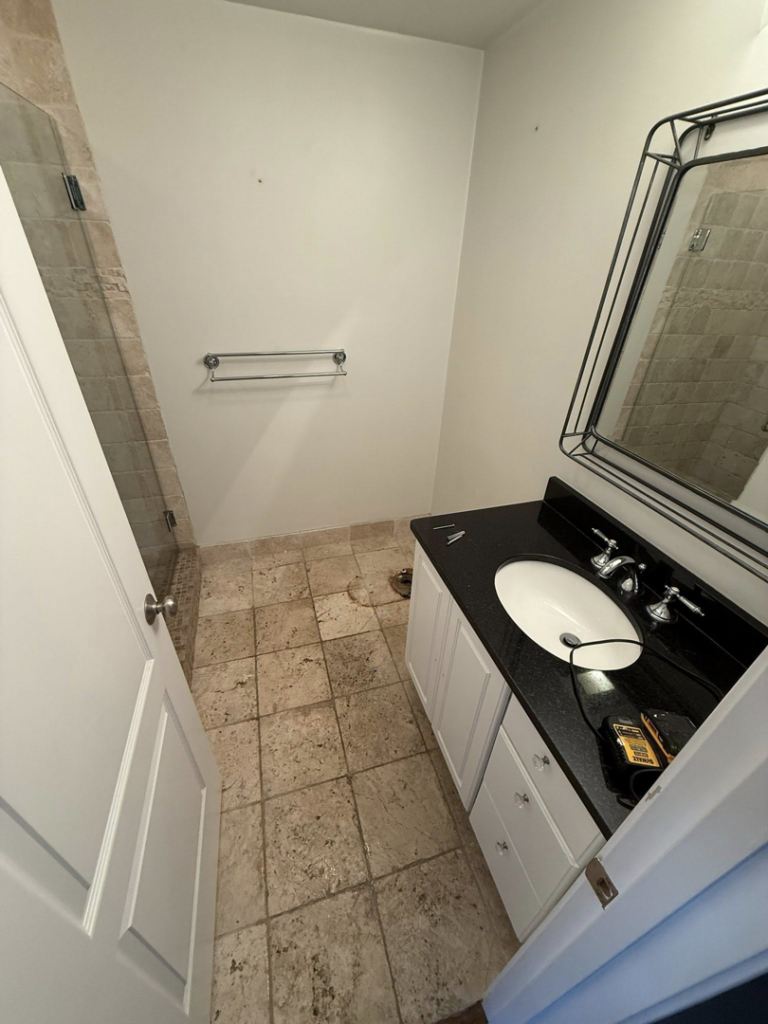 A newly installed bathroom vanity with a black countertop and mirror, along with a towel bar, by MS Renovation in Boston, MA.