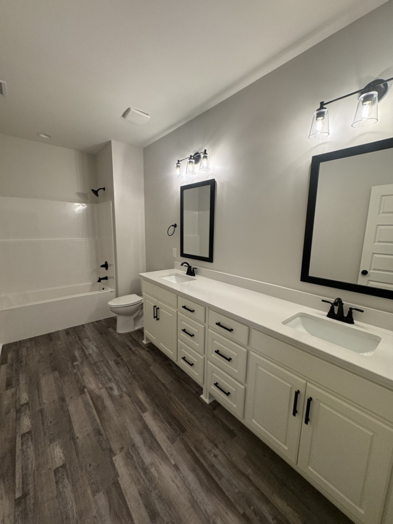 A newly renovated bathroom featuring double vanity, mirrors, and light fixtures installed by Adamson Construction Group in Salem, AL.