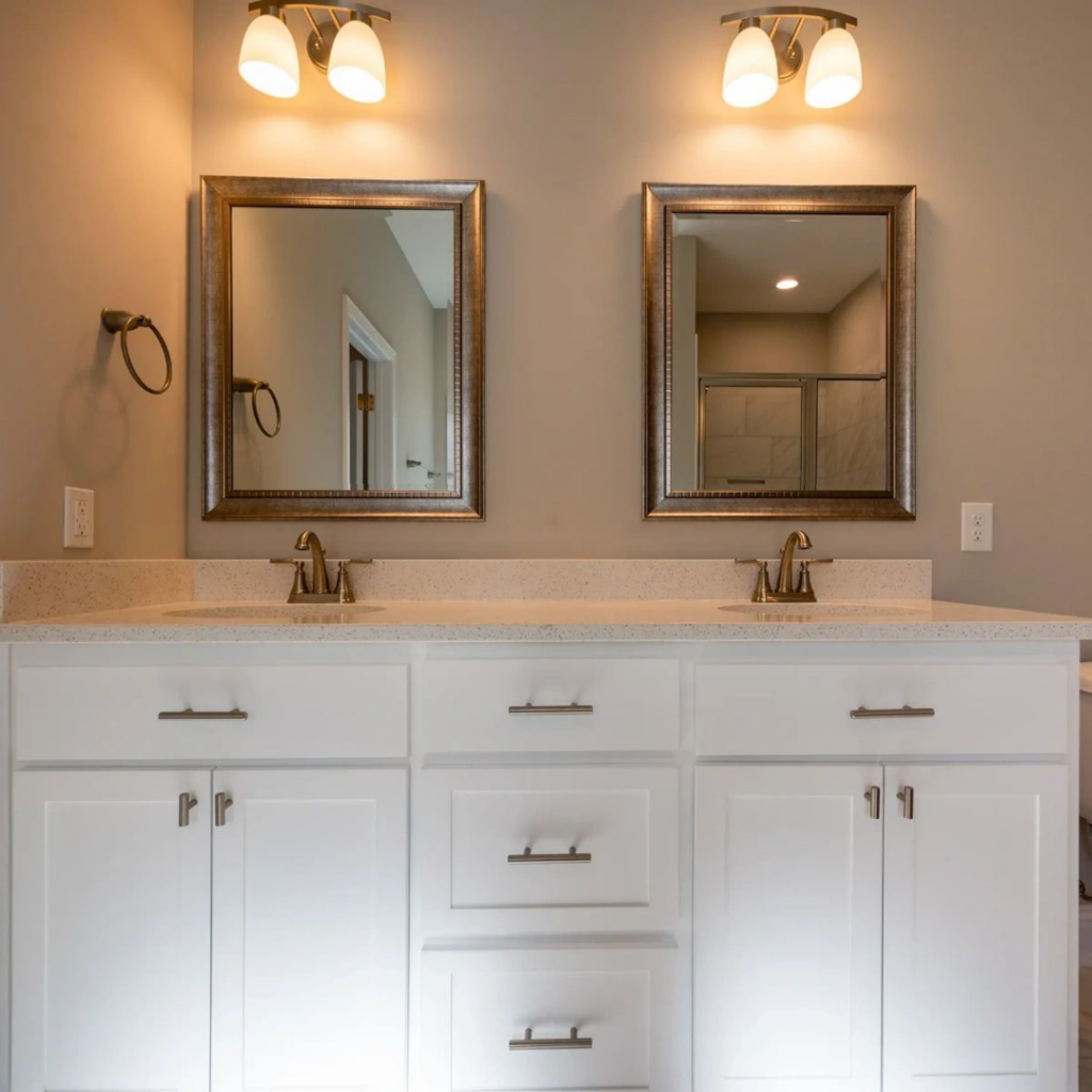 A newly installed bathroom vanity with dual sinks, mirrors, and light fixtures by Daniel Builders, LLC in Montgomery, AL.