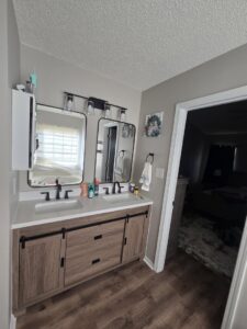 A renovated bathroom with a new double vanity, mirrors, and light fixtures installed by Home FREA in Raleigh, NC.