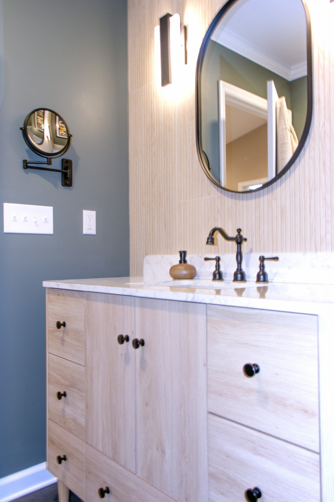 A modern bathroom vanity with a new sink, faucet, mirror, and light fixture installed by Renew Additions & Remodeling, LLC in Columbus, OH.