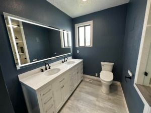 A renovated bathroom showcasing a double vanity with an illuminated mirror by DSM Construction in Evanston, WY.