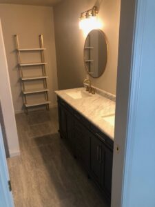 A newly installed bathroom vanity with a marble top, gold fixtures, mirror, and ladder shelf by The Huckleberry Handyman in Meridian, ID.