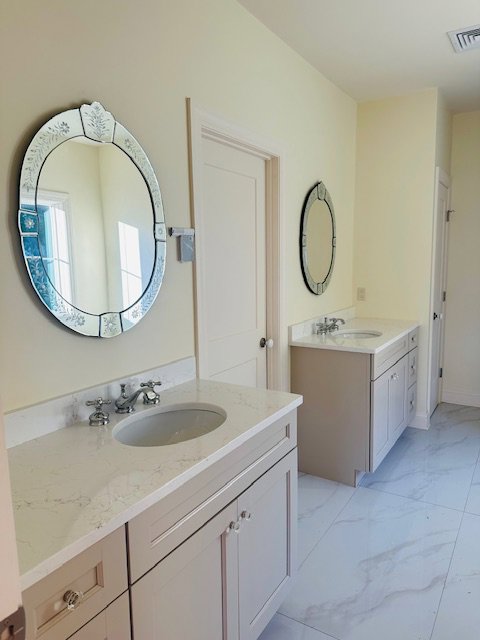 A renovated bathroom with new vanities, mirrors, and tile flooring by R&J Handyman Services LLC in Warwick, RI.