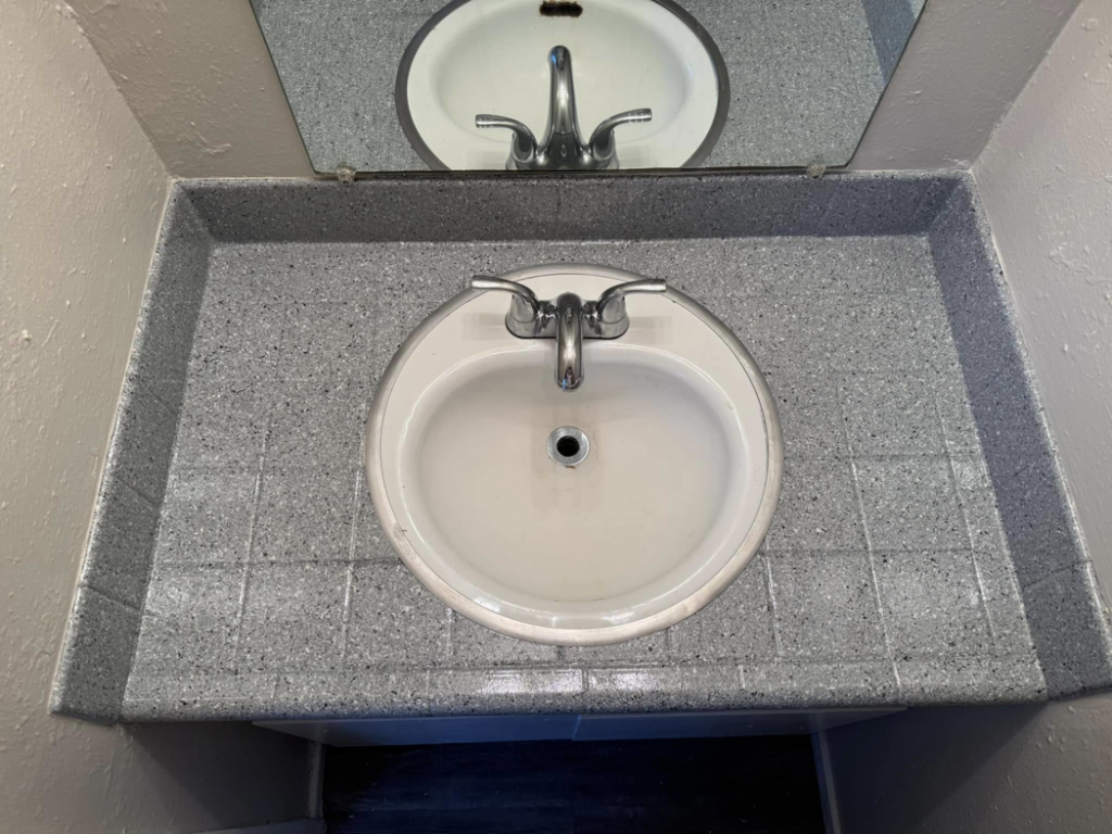 A newly resurfaced grey speckled bathroom vanity and sink by That Resurfacing Guy LLC in Oklahoma City, OK.