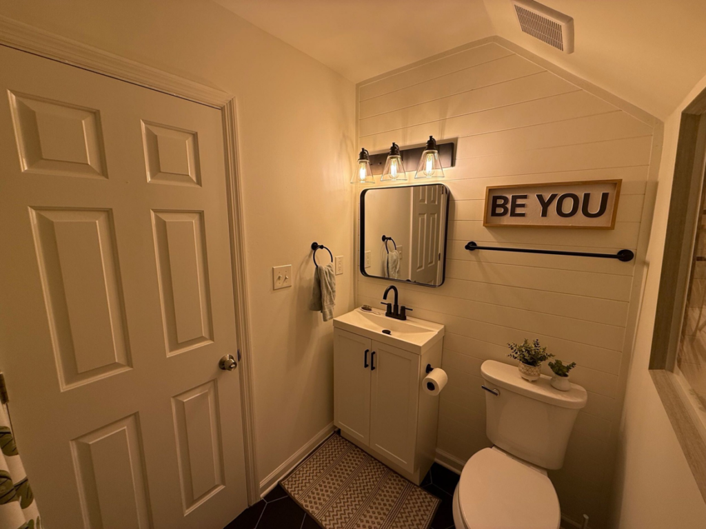 A newly updated small bathroom with a modern vanity, mirror, light fixture, and shiplap accent wall, installed by Safe Haven Home Services in Nashville, TN.