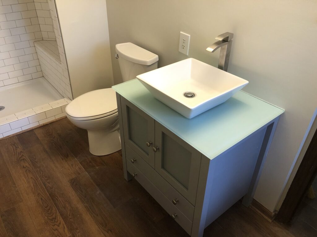 A renovated bathroom featuring a new vanity, vessel sink, and toilet by E.L. Construction in Kansas City, MO.