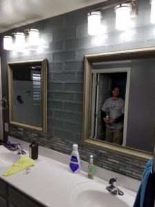 A bathroom vanity with a newly installed tile backsplash, mirrors, and lighting by Clayton Family Tile, LLC in Chandler, AZ