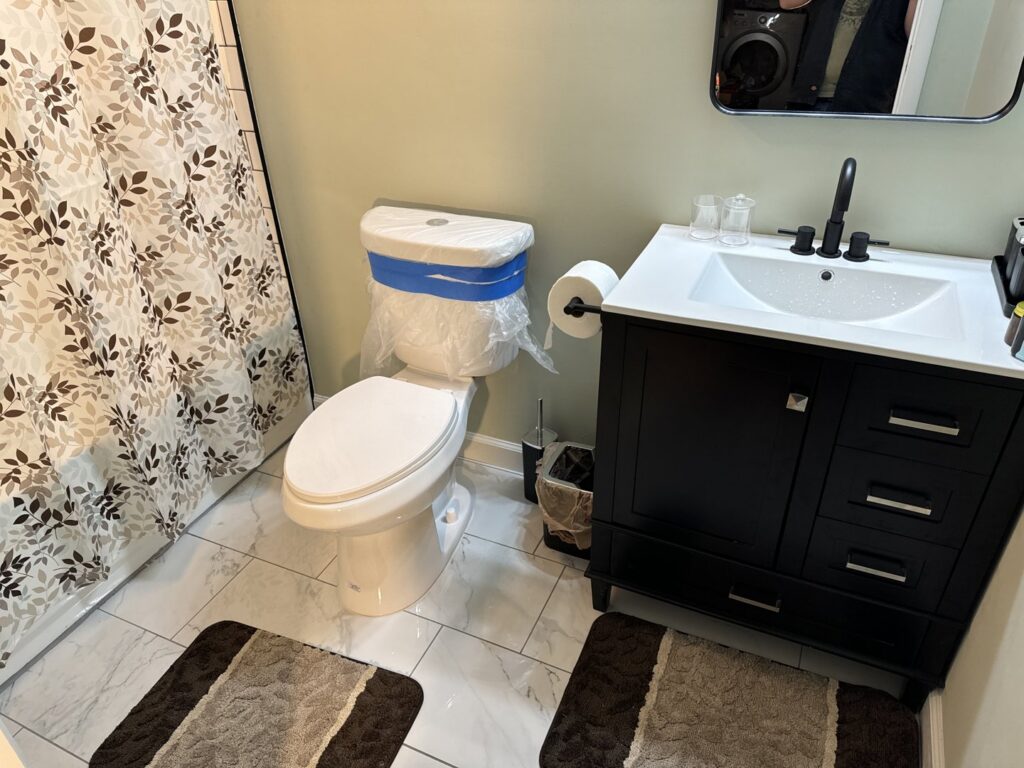 A newly renovated bathroom featuring a new toilet, vanity, sink, and faucet, completed by Jake and Jake Construction LLC in Sandy, UT.