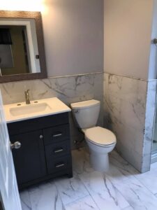 A renovated bathroom with a new vanity, toilet, and marble-look tile on walls and floor by Pro Remodel LLC in St. Charles, MO.