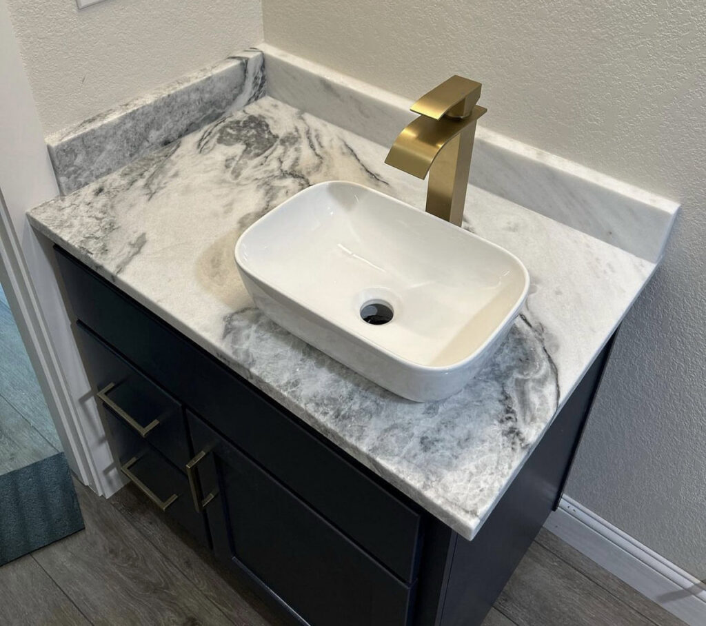 A stylish bathroom vanity with a dark cabinet, a modern vessel sink, and a marble-look countertop installed by Javier's Countertops in Springdale, AR