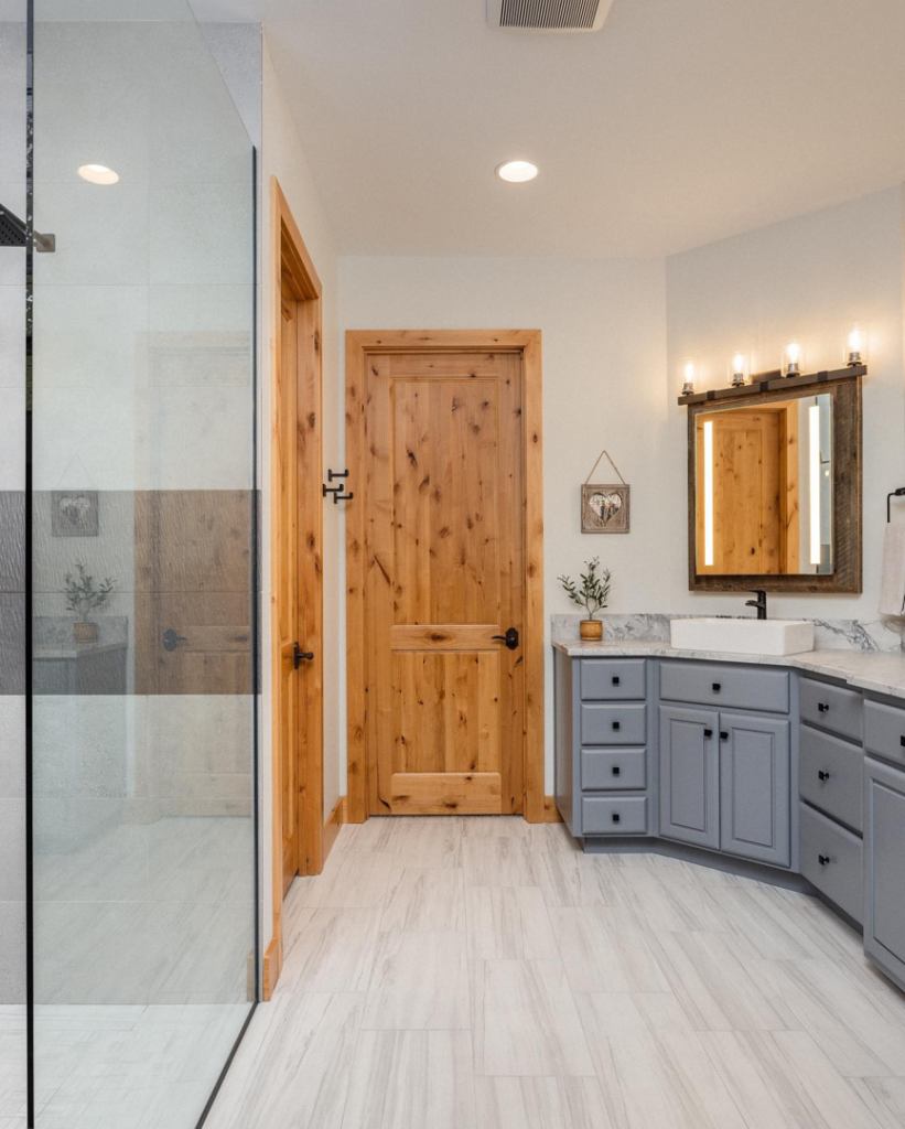 A bathroom remodel with a grey vanity, vessel sink, and glass shower enclosure by Nelson Tile and Stone in Bend, OR.
