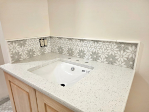 A new bathroom vanity with a quartz countertop and floral tiled backsplash installed by Tyler the Tiler in Jefferson, WI.