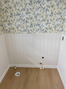 Bathroom with white wainscoting, floral wallpaper, and plumbing rough-ins for a toilet and sink by LIV Custom Accents in West Fargo, ND