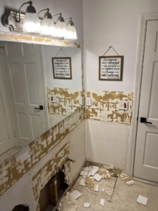 Bathroom wall exposed after tile removal during renovation, debris on floor, by JTL Contracting Services LLC in Inver Grove Heights, MN