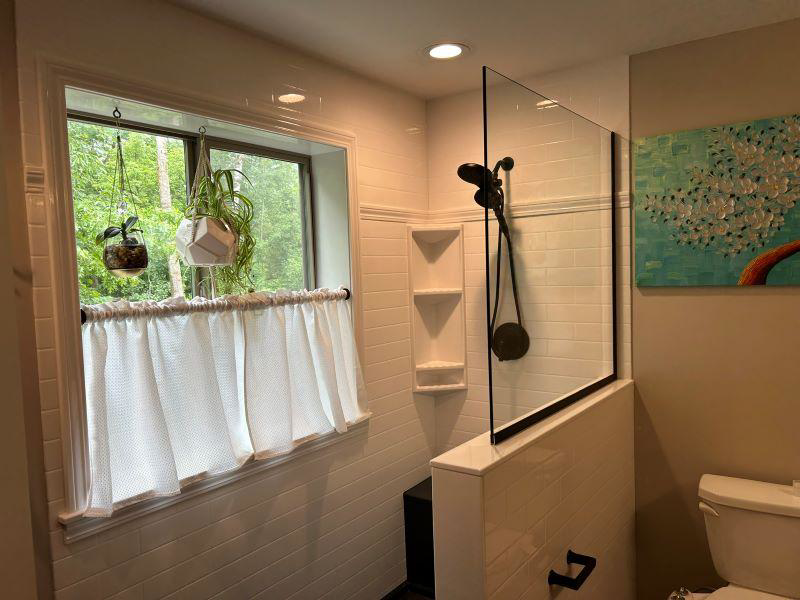 A renovated bathroom featuring a glass shower enclosure and white tiled walls by VanVleet Construction in Brooklyn Park, MN.