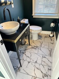 A renovated bathroom featuring a stylish marble-look tile floor and a unique vanity installed by Tile Jawn in Philadelphia, PA.