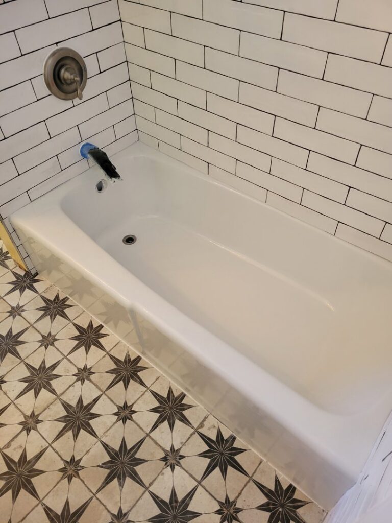 Renovated bathroom with refinished tub, white subway tiles, and patterned floor by Phillys Finest Tub & Tile Refinishing in Philadelphia, PA