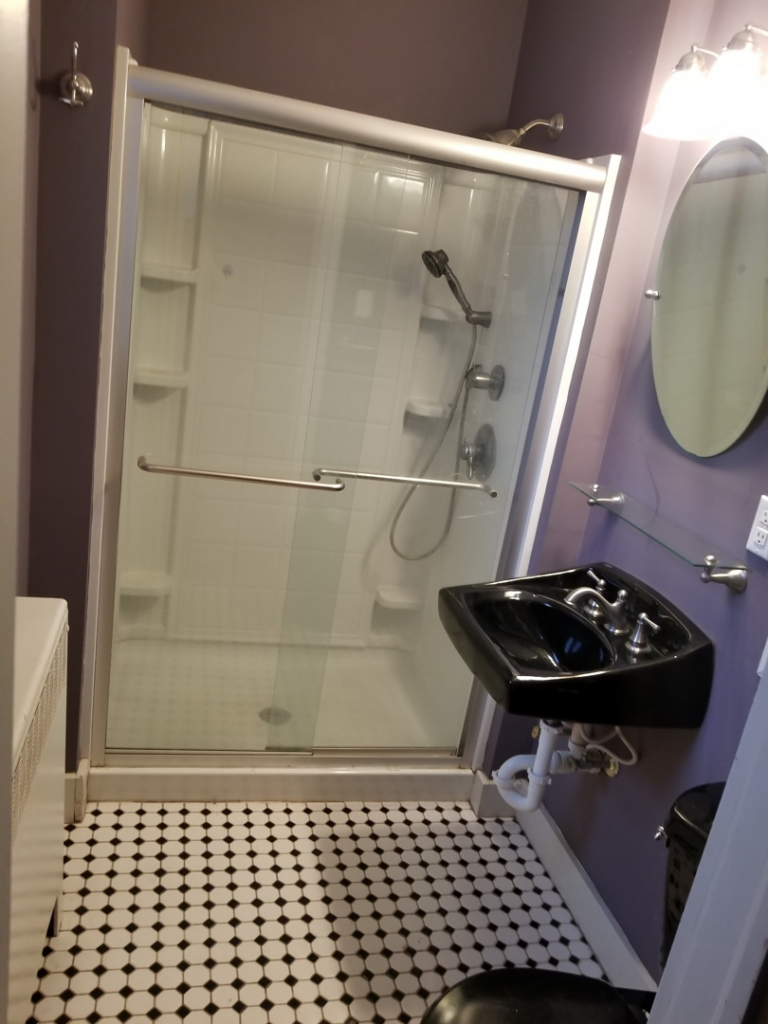 A renovated bathroom featuring a shower enclosure and a modern wall-mounted sink by DBB, Inc. in Harrisonburg, VA.
