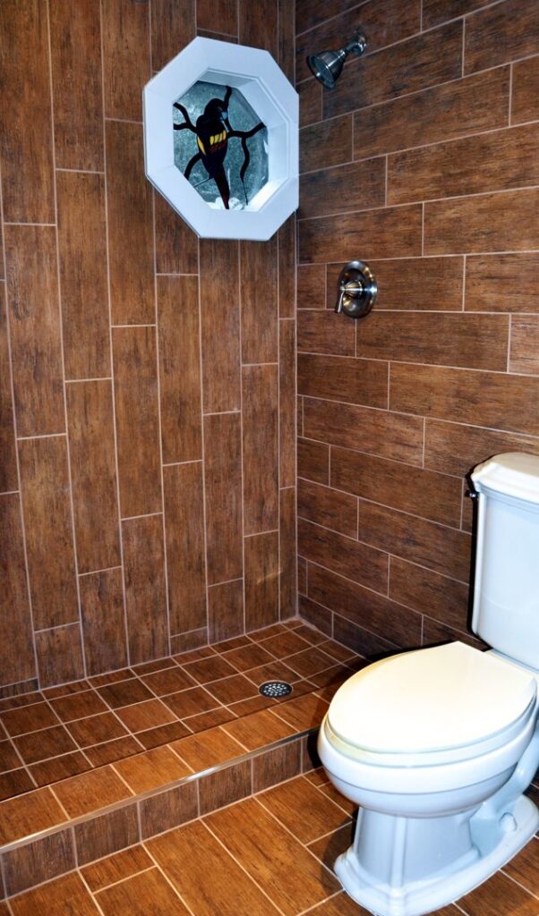 A remodeled bathroom featuring wood-look tile on the walls and floor, with a modern shower and toilet by JNY Remodeling INC in Fort Lauderdale, FL.