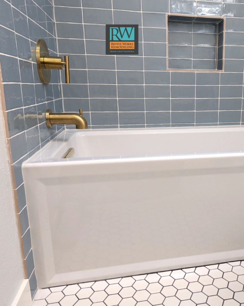 A newly installed bathtub with blue subway tiles and brass fixtures by Revive Works Remodeling in Portland, OR.