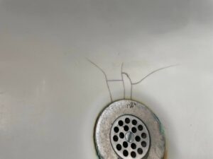 Close-up of a bathtub drain with cracks in the enamel, indicating a need for repair by Home Pros WV in Charleston, WV.