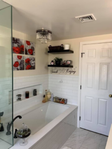 A newly installed bathtub area with subway tiling and a modern light fixture by Solis and Son Construction in Denver, CO.
