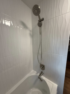 A newly installed bathtub and shower combo with modern wavy wall tiles by River Oak Renovations in Augusta, GA.