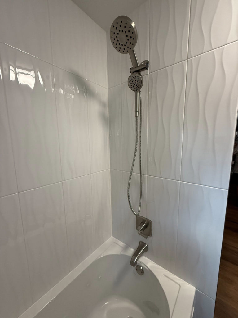 A newly installed bathtub and shower combo with modern wavy wall tiles by River Oak Renovations in Augusta, GA.