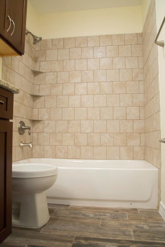 A renovated bathroom showcasing a bathtub and shower combination with new tiling, completed by Custer Remodeling in Plano, TX.