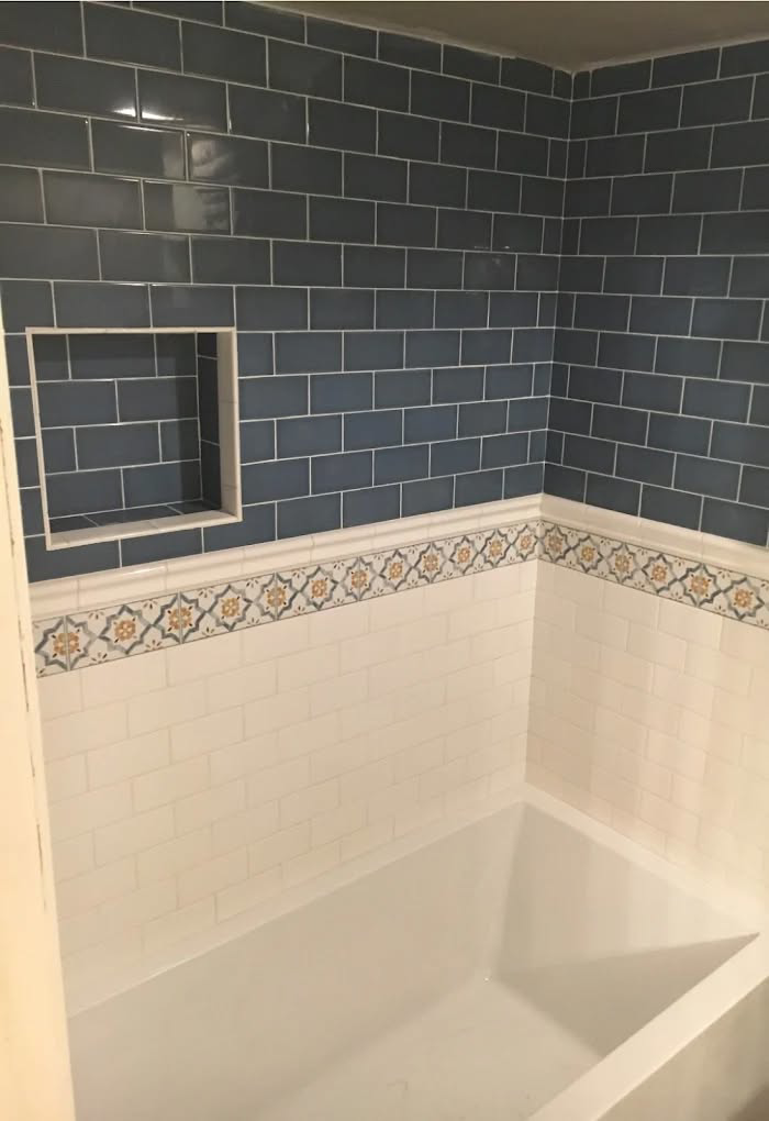 Bathtub with new blue and white subway tile surround and decorative border installed by B&W Designer Tile in Tulsa, OK