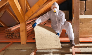 Worker installing batt insulation in an attic for CT Insulation Services LLC in Stamford, CT