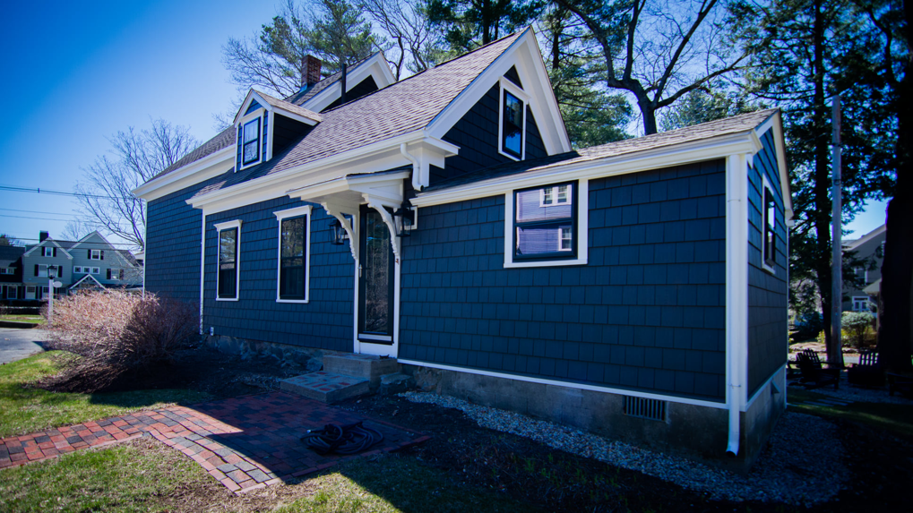A close-up of a bay window with dark shutters and white trim on a house exterior by Boston Exterior Remodeling in Boston, MA.