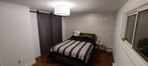 A bedroom with a wood-paneled accent wall and modern barn doors installed by NP General Contracting in Austin, TX.