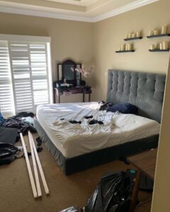 A messy bedroom with clothes and debris on the floor, ready for cleanout by The Junk Gentlemen in Anaheim, CA.