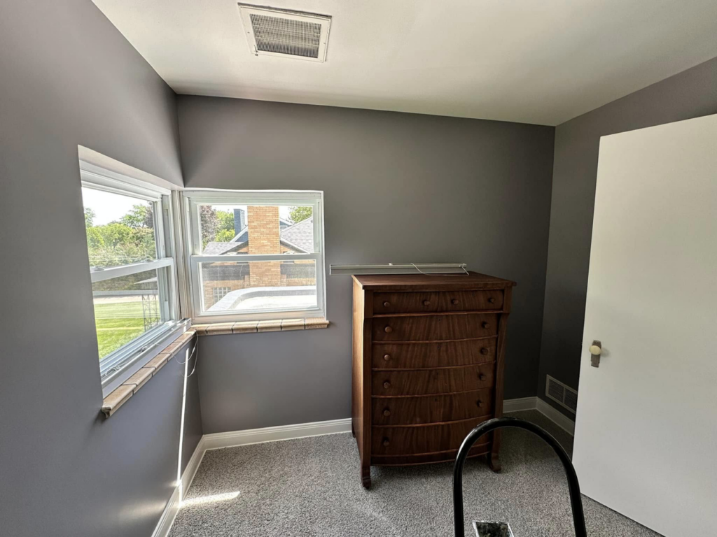 A bedroom with freshly painted gray walls and a ladder, showcasing painting services by EJ Drywall Plus in Kearney, NE.