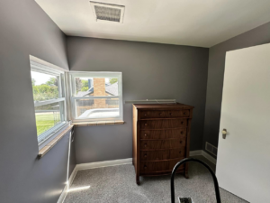 A bedroom with freshly painted gray walls and a ladder, showcasing painting services by EJ Drywall Plus in Kearney, NE.