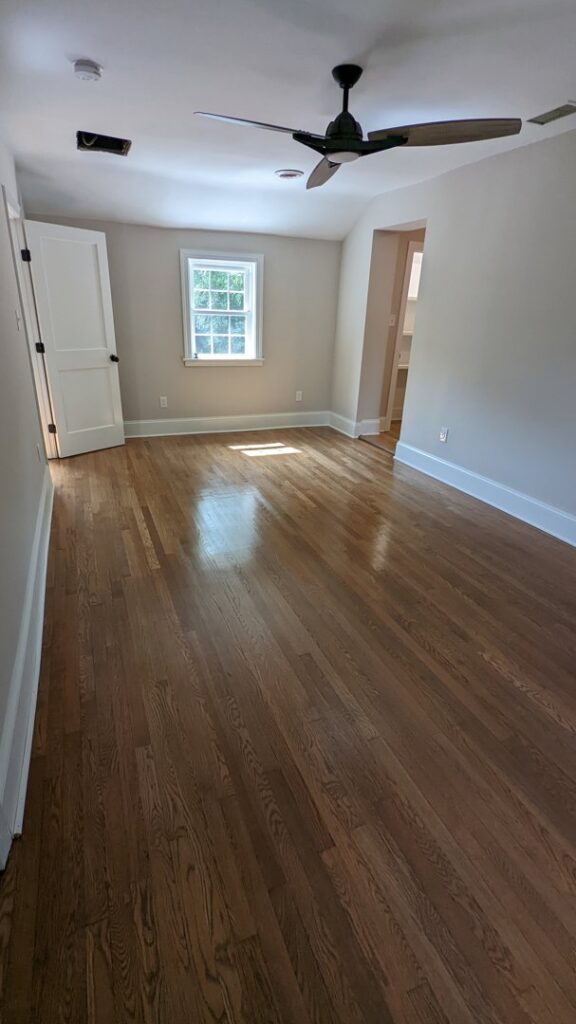 A newly painted bedroom with hardwood floors and a ceiling fan by Global Painting RVA in Richmond, VA.