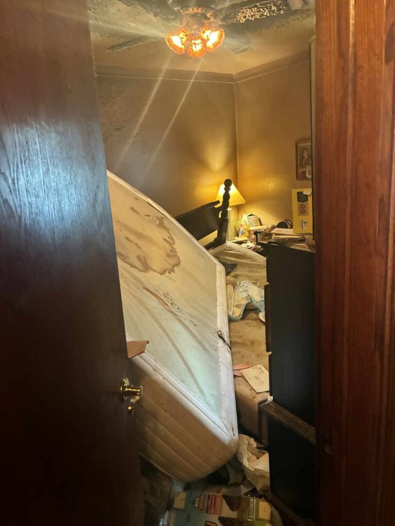 A severely cluttered bedroom with a mattress and piles of trash, ready for junk removal by Feelin Good Junk Removal & Estate Sales at 1111 Debra Lane.