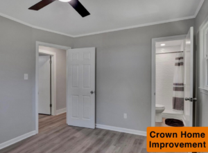A renovated bedroom with new flooring and a view into a modern bathroom with a tiled shower by Crown Home Improvements in Charlotte, NC