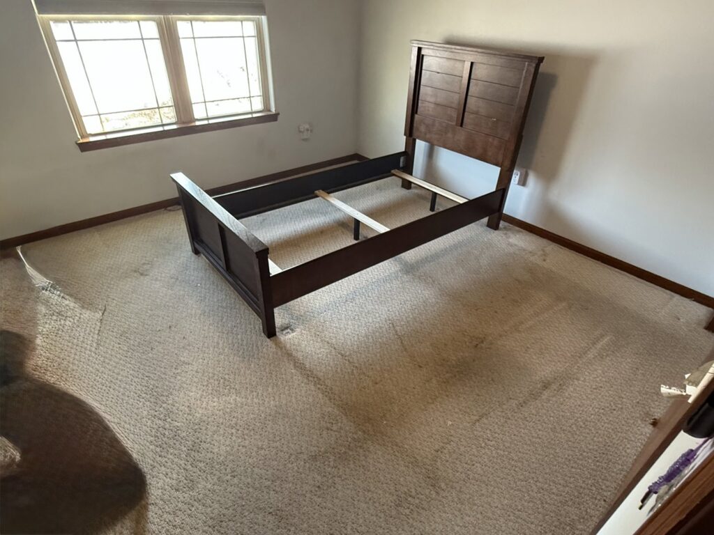A bedroom with old carpet, prepared for new flooring installation by D E Custom Floors in Waukesha, WI.